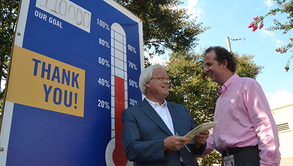 DAILY LEADER / RACHEL EIDE / Bill Sones (from left) and Jason Snider discuss plans for the local United Way fund drive. Sones is president of the United Way of Lincoln County board and Snider is the campaign chairman. As the "thermometer" in front of the Brookhaven-Lincoln County Chamber of Commerce shows, the campaign is 50 percent of the way toward reaching its $110,000 goal.