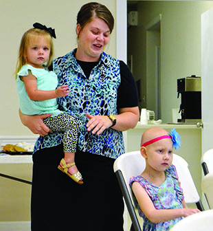 As daughter Kalie Wilkerson, (above right) 7, listens, her mother Jessica Wilkerson, holding 2-year-old Jolie, talks about how much Kaley's Make-A-Wish Disney trip meant for their family.