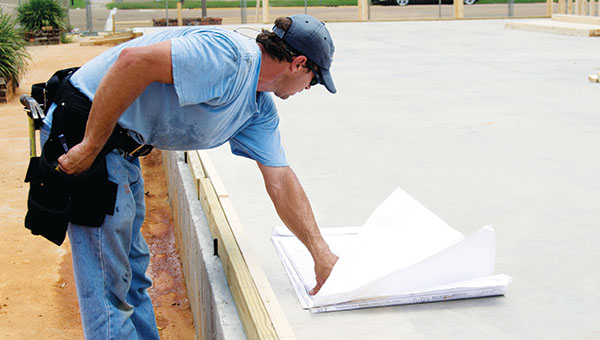 DAILY LEADER / RACHEL EIDE / Bubba Dooley, with DWD Construction, reviews the plans before starting work on the north wall Tuesday afternoon.
