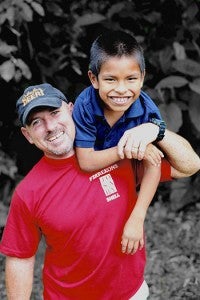 Jeff Freeman carries Casa de Fe resident Martin to school. The nine-year-old has braces on his legs, and rainy weather makes it difficult for him to cross the rough Ecuadorian terrain.