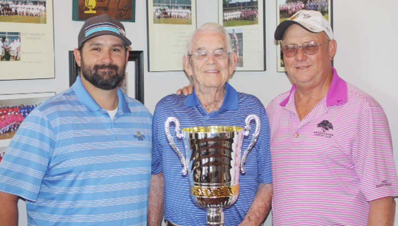 DAILY LEADER / Photo Submitted / Wolf Hollow Club team captain Alex Shoemake (left), and Brookhaven Country Club team captain Glynn Murray (right) gladly pose with Mr. Ed Norwood and his Cup as they get ready to lead their teams to victory this weekend. Competition begins Saturday morning at 10 with a nine-hole, alternate shot format. After lunch, a four-ball match play tournament will be held at the Wolf Hollow Golf Club, starting at 1 p.m. Individual matches are set for Sunday at the Brookhaven Country Club, beginning at 1 p.m.