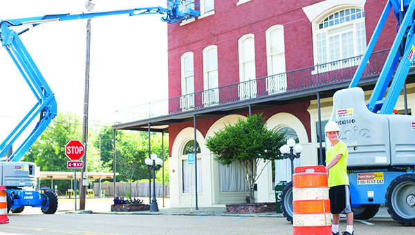 Photo by Kaitlin Mullins Noah Barnett, 12, helps direct traffic around the Inez building Thursday morning. For the last couple of days, Barnett has been helping his dad (on the lift, not pictured) while he and others paint and do some repairs on the sky-high lifts. Barnett said he is having fun helping out, especially directing traffic, which is exciting as well as an important job.
