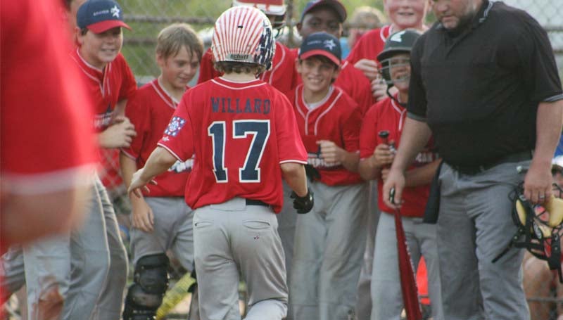 DAILY LEADER / MARTY ALBRIGHT / Lincoln County Americans' slugger Dakota Willard (17) is greeted at home plate by his teammates after hitting a solo home run in the fifth inning against the Lincoln County Nationals Monday night in Bude.