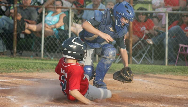 DAILY LEADER / MARTY ALBRIGHT / Lincoln County Americans' Easton Sartin (2) slides into home plate safely against Lincoln County Nationals catcher Logan Case Wednesday night.