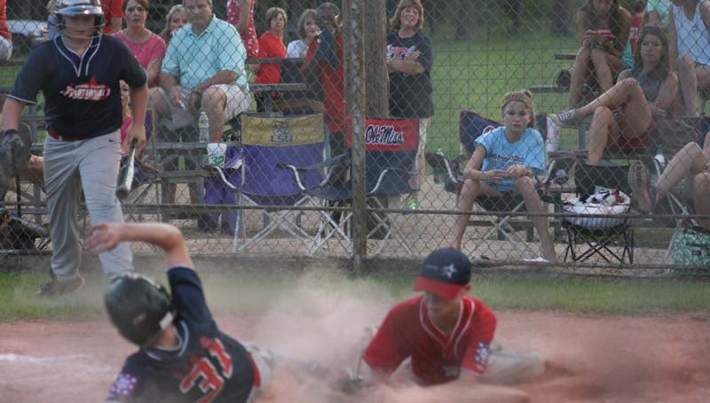 DAILY LEADER / MARTY ALBRIGHT / Lincoln County Nationals' runner Dylan Carter slides into home plate safely before Americans pitcher Tyler Fortenberry could make the play Friday night.
