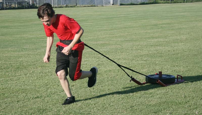 DAILY LEADER / Evan Kyzar works on his endurance while pulling a weighted sled during Bogue Chitto's summer workout.
