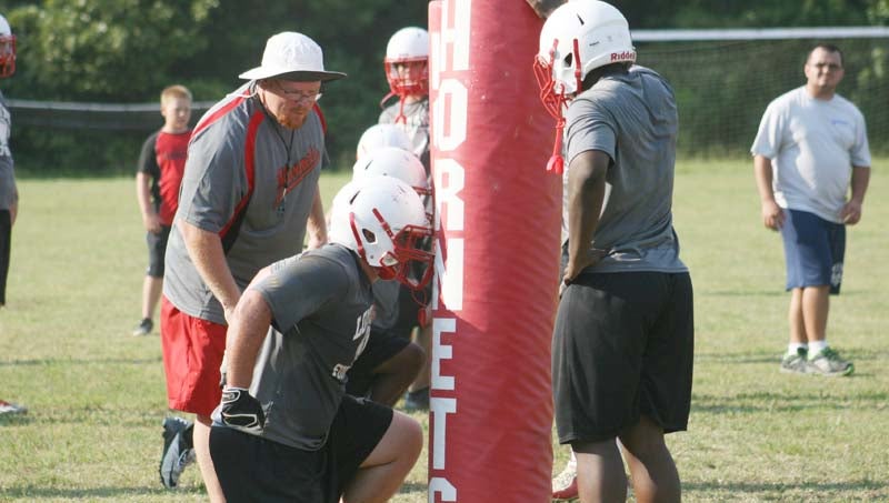 DAILY LEADER / MARTY ALBRIGHT / Loyd Star's Bradyn Brister (left) works on his tackling technique as teammate Anfernee Claire (right) holds up the tackling dummy and Coach Adam Cook looks on.