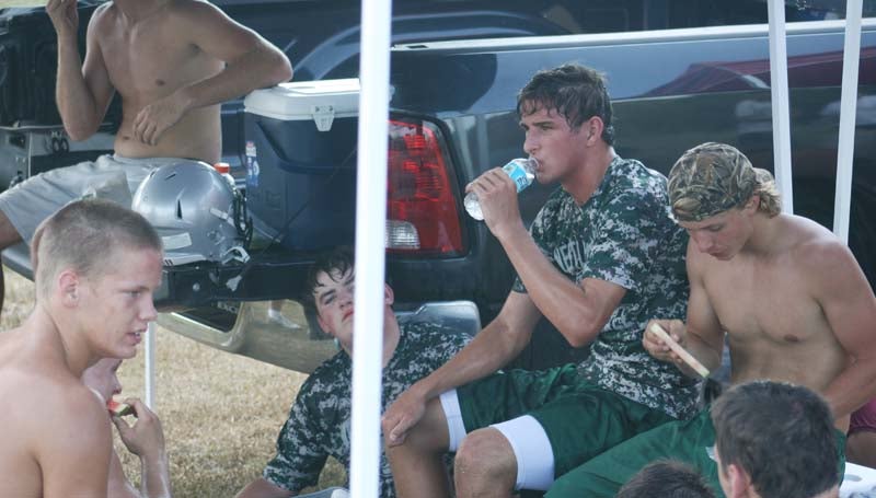 DAILY LEADER / MARTY ALBRIGHT / West Lincoln's football players enjoys a break from the heat as they rest under a tent to drink water and eat some fruit furnished by KDMC Performance Center Wednesday afternoon.