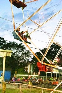 Fair patrons wave from the Ferris wheel at the Exchange Club Fair Wednesday night