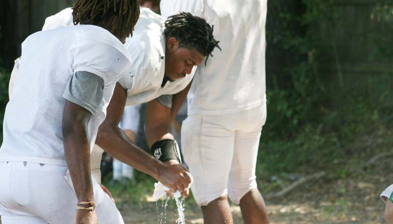 DAILY LEADER / Marty Albright / Lawrence County's football players take a break from the heat to apply ice cold, wet towels to their neck or head to cool down during their water break.