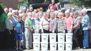 Photo by Aaron Paden Volunteers stand with some of the buckets they filled with hospice supplies Monday. 