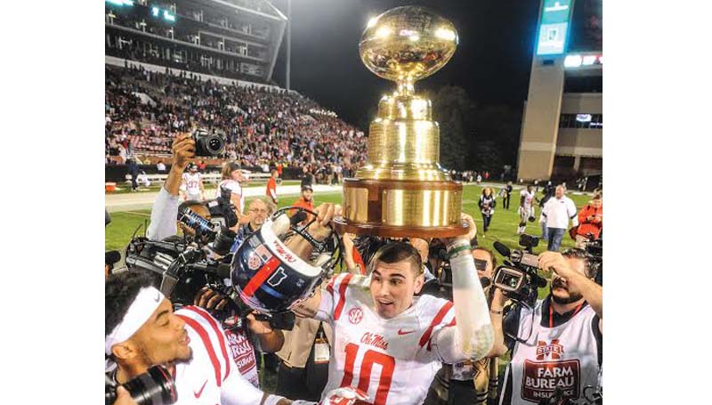 Bruce Newman/Oxford Eagle / Ole Miss quarterback Chad Kelly hoists the Egg Bowl trophy in the air in celebration Saturday night in Starkville.