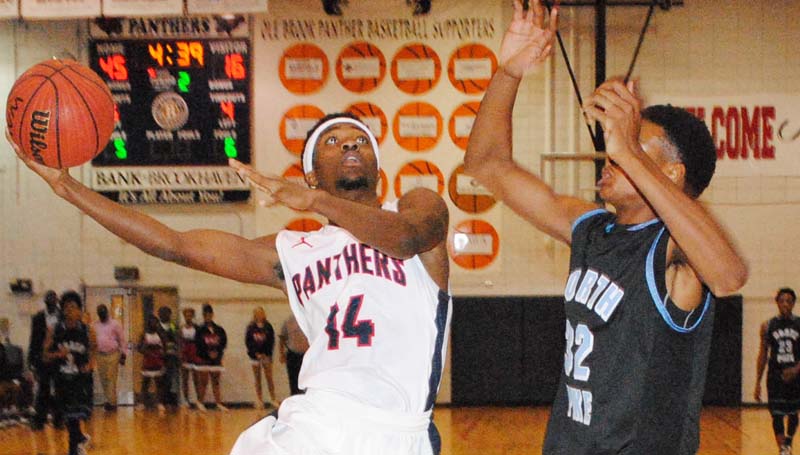 Daily Leader / Marty Albright / Brookhaven Damarius Brooks (14) glides through the lane to make an acrobatic layup over North Pike's LeTravion Bankham (22) Friday night.
