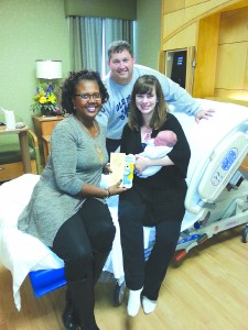 Rita Robinson, left, presents Mike and Rachel Powell and their son, James Robert Powell, with a book from the Cuddle Up program.