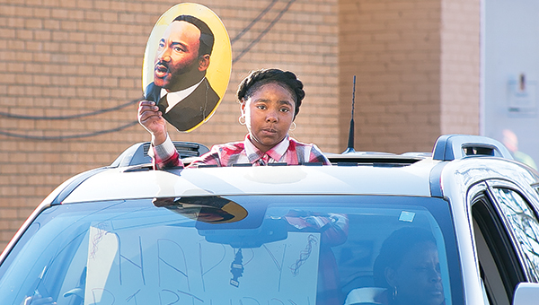 Photos by Kaitlin Mullins / Above, a young lady peeks from a sunroof holding a photo of Dr. Martin L. King Jr. Drive during the Sunday parade. Brookhaven Police Chief Bobby Bell led the convoy, followed by fire trucks and parade organizer Bernetta Character followed in the last vehicle in the parade. Left, a young man joins a pack of motorcyclists in the parade honoring Martin Luther King Jr. that made its way through downtown Brookhaven on Sunday.