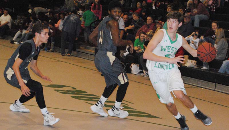 Daily Leader / Marty Albright / West Lincoln's Adam Martinez (15) drives past two Enterprise defenders in boys action Tuesday night at Jack Case Gymnasium.