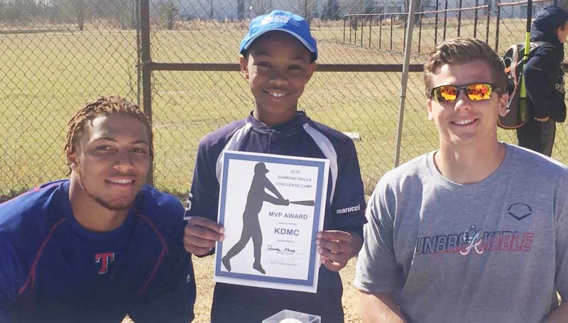 Daily Leader / Photos by James O. Covington / Donovan Moore receives the KDMC MVP Award at the Franklin County Diamond Skills MLB Kids camp by Texas Rangers' Ledarious Clark and Atlanta Braves Bradley Roney.
