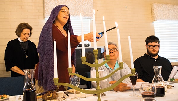 Photos by Julia Miller / DeAna Derrick lights the Festival of Lights on the Menorah as “mother” during the annual Seder Supper ceremony at the Episcopal Church of the Redeemer on Maundy Thursday.
