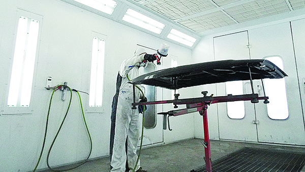 Photo by Aaron Paden / Jon Thames sprays a customer’s door Thursday in a room designed specifically for applying paint.