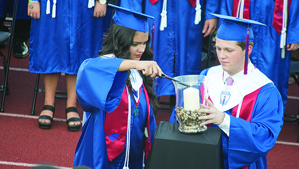 Photo by Julia Miller / Brookhaven High School student council president Jaylynn Thompson and Fellowship of Christian Athletes president Taylor Pendley light a candle in honor of Nealey Brown during Friday’s graduation. Brown, who graduated in December from BHS, died in a car accident earlier this spring.