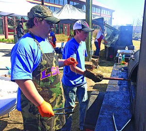 Sam Edwards (left) and Zach Jenkins fire up the smoker during one of the Smokin’ Hornets Cooking Team’s competitions this year.