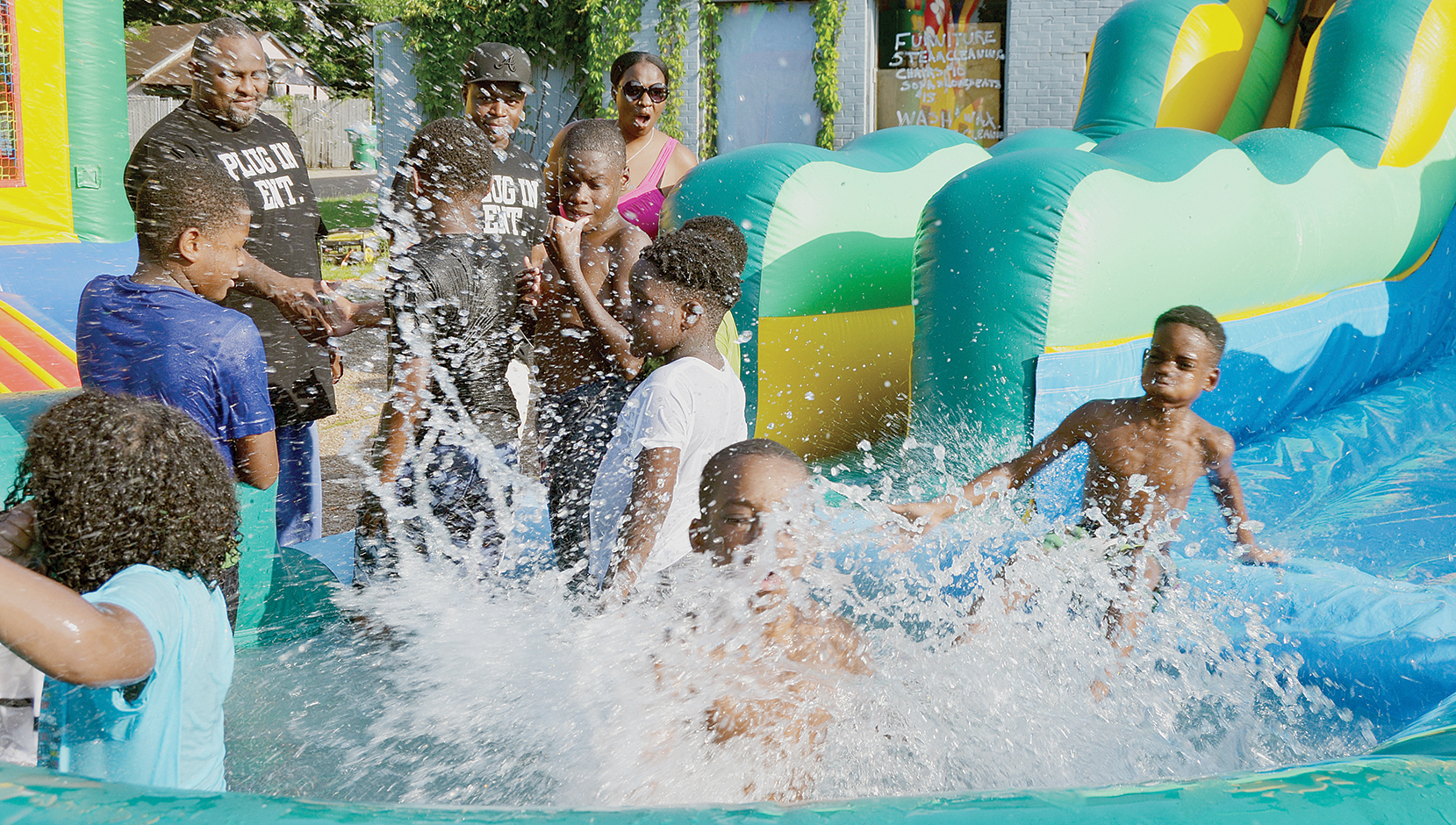 Photo by Donna Campbell/Triston Allen, 9, the son of Samantha Allen of Wesson, makes a huge splash as he slides into the inflatable pool set up in a business parking lot at the corner of Avalon and East Monticello streets.