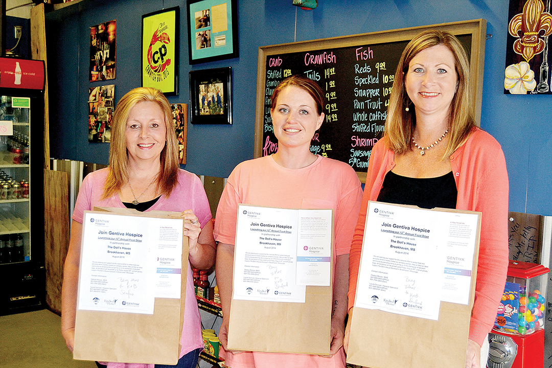 Photo by Donna Campbell/K&B Seafood owner Becky Allen (left), store manager Liz McDaniel and Gentiva Hospice representative Laurie Sullivan show the bags that can be filled with non-perishable goods and personal hygiene items to be donated to Doll’s House in Brookhaven.