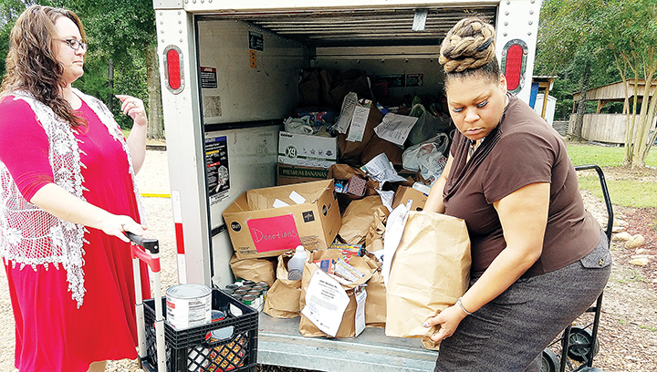 Photo by Donna Campbell/Sara Skinner, a nurse with Gentiva Hospice, (left), and Gentiva Executive Director Erika Newsome help unload some of the 2,673 pounds of food collected in the company’s 12th annual food drive. The food was donated to The Doll’s House in Brookhaven.