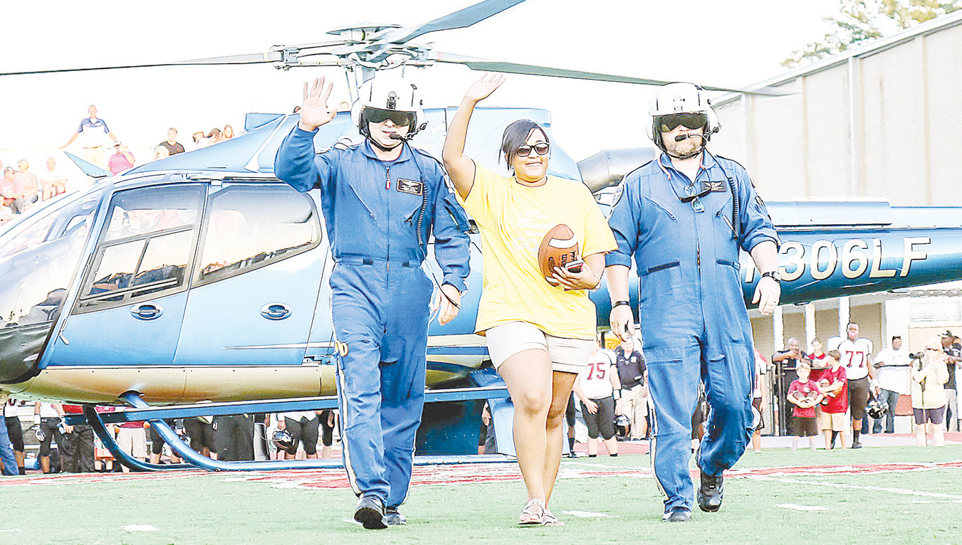 Photo submitted/The crew with LifeFlight-4 out of Brookhaven flew in Brookhaven High School alumni Chasity Gayten (center) a cancer survivor, to deliver the game ball at a recent game. Gayten, a kindergarten teacher’s assistant at Mamie Martin Elementary, was diagnosed with breast cancer during her senior year in 2008. With Gayten are Ricky Pittman (left) and Jack Hourgettes. Not pictured is pilot Ryan Meador.