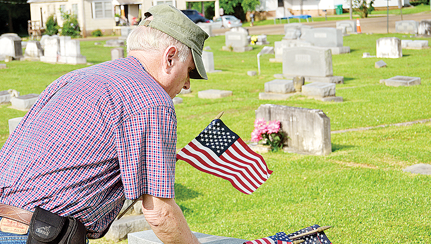 Photo by Donna Campbell/American Legion Post Commander Keith Reeves places American flags at Rosehill Cemetery earlier this year. Volunteers are needed Saturday at 8:30 a.m. at the Rosehill, East Haven, Carver Heights and Hillcrest cemeteries to mark the graves of deceased veterans as a Veterans Day tribute. Volunteers will also be needed the following Saturday at the cemeteries to pick up the flags.