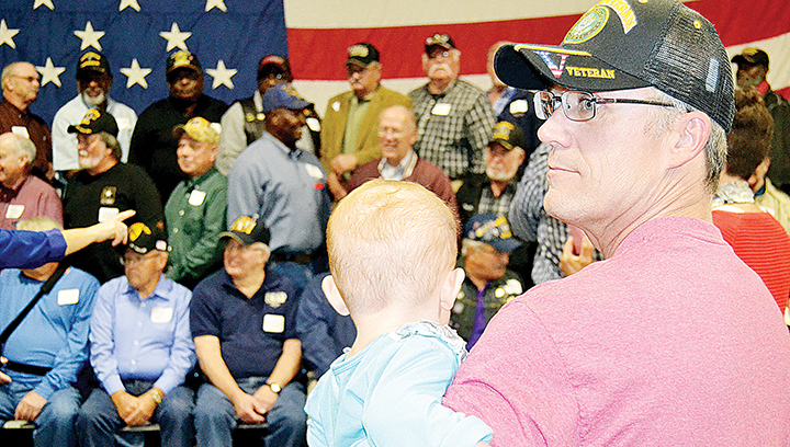 Photo by Donna Campbell/Roy Barnett Jr. holds his granddaughter, 2-year-old Delilah Barnett, while his father gets his group photo taken. Barnett, of East Lincoln, served in the Army in Desert Storm, while Roy Barnett Sr., of West Lincoln, served as a Marine in Vietnam.