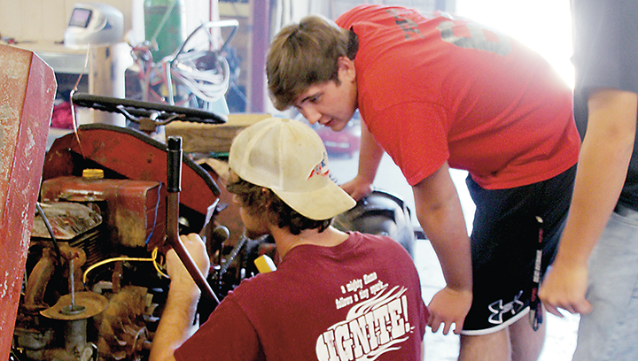 Photo by Alex Jacks/Loyd Star Agriculture Academy students Stewart Thomas (left) and Canon Travis examine a 1920s tractor in the school’s shop that they'll restore to its original condition for the owner.