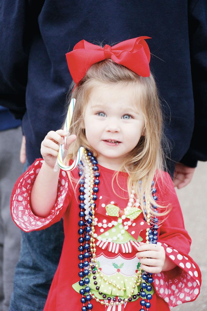 A toddler waits anxiously for Santa while snacking on a candy cane she caught from one of the floats in the 44th annual Wesson Christmas parade. Children of all ages gathered along the streets of downtown Wesson Friday to admire the floats.