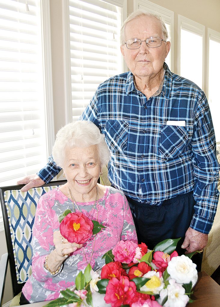 Photo by Donna Campbell/Betty Peters (left) and Frank Burns enjoy the fragrance of fresh-cut camellias in the sunroom at BeeHive Homes in Brookhaven. Peters’ late husband, Howard, and Burns’ late wife, Kay, will be honored Saturday at the 54th annual Camellia Show hosted by the Brookhaven Camellia Society at the Brookhaven Recreational Center. The event is open to the public after the judging. 